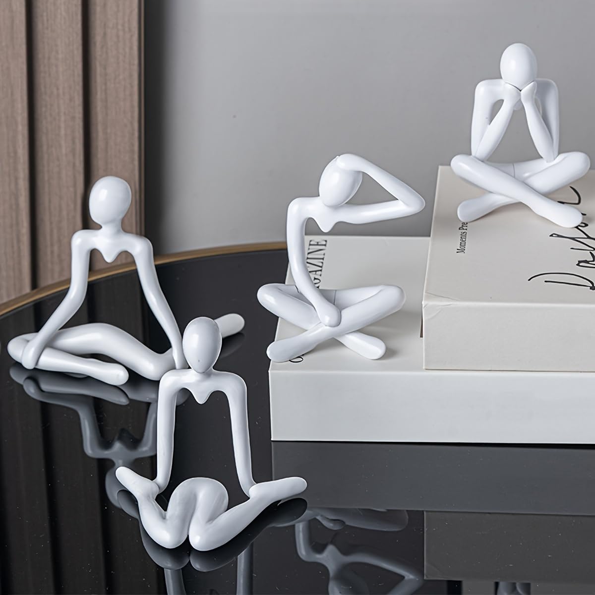 White abstract human-like figures on a reflective surface with a neutral background