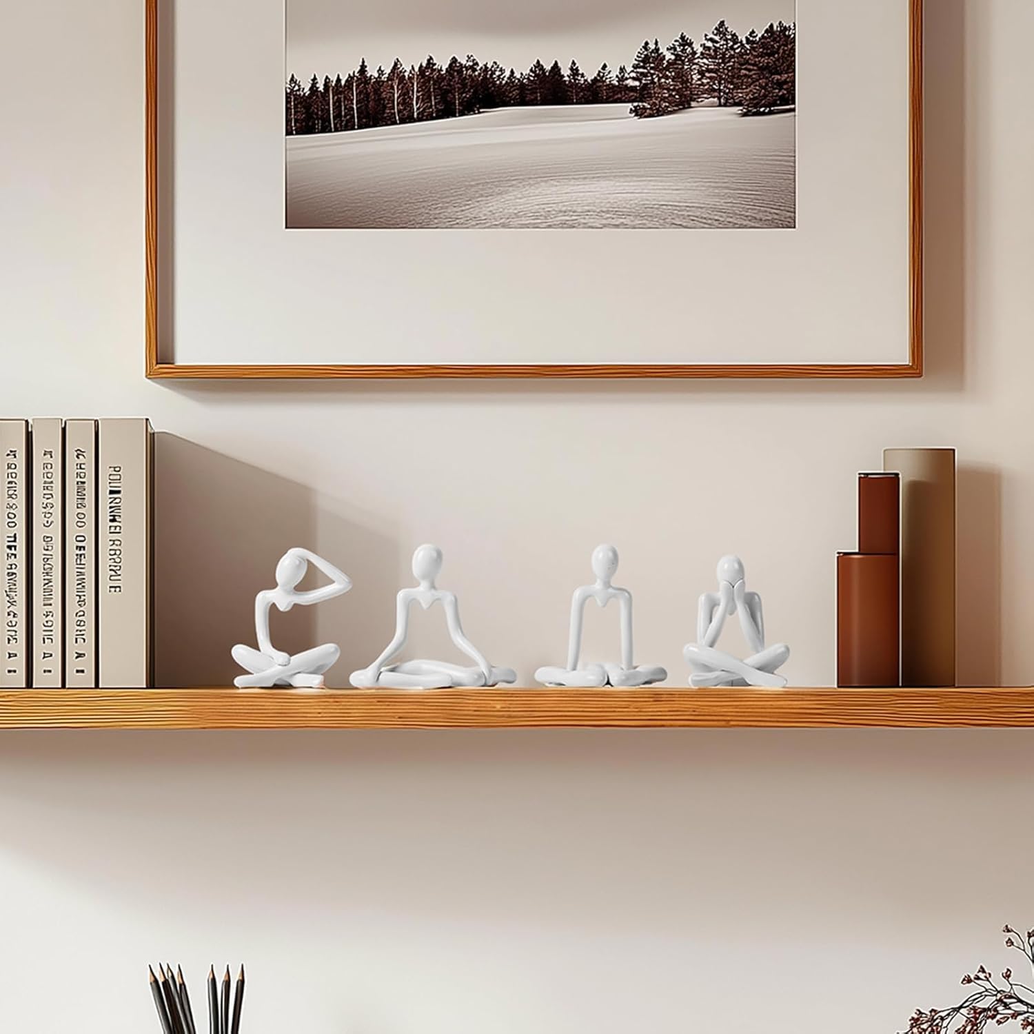 Decorative shelf with white sculptures, books, and a framed landscape print on a beige wall.