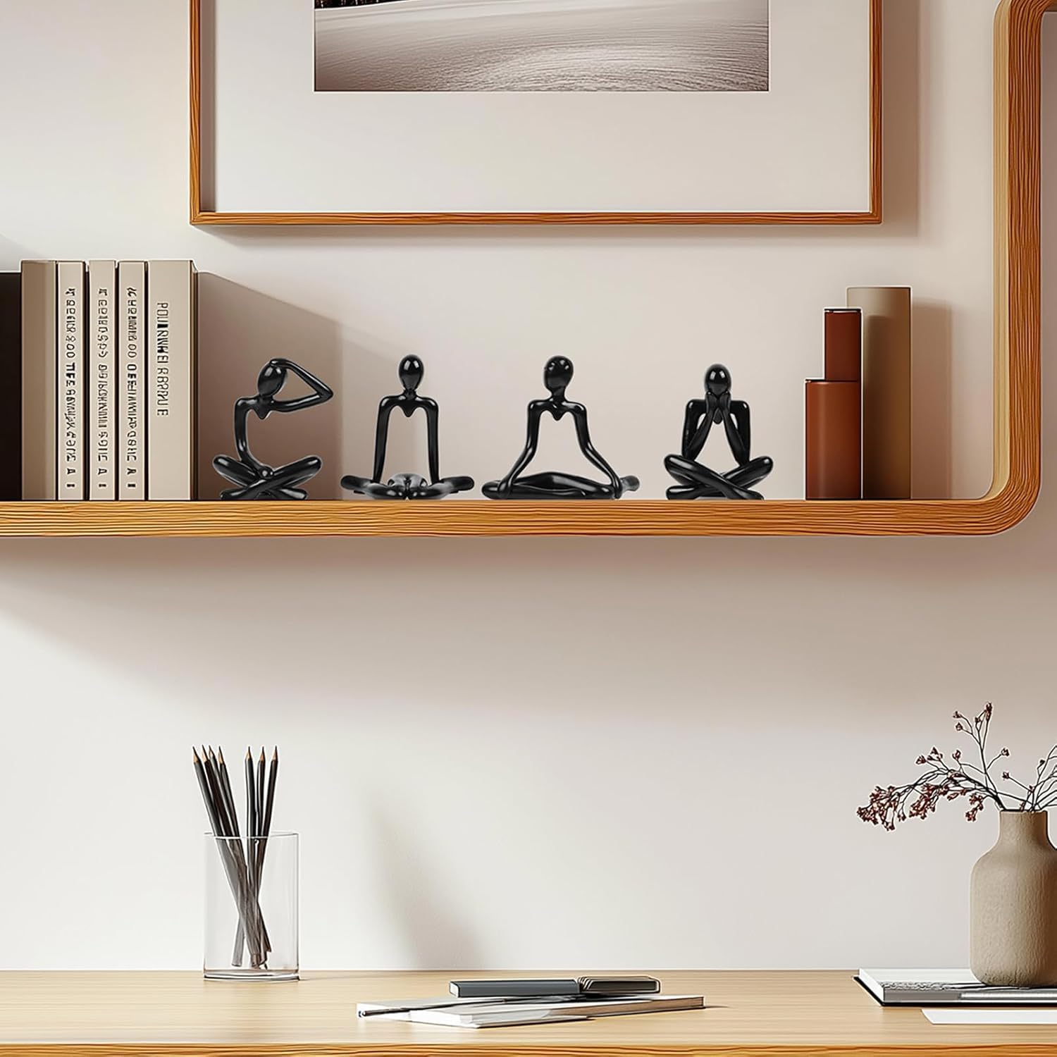 Decorative shelf with black figurines, books, and a vase on a light-colored wall.