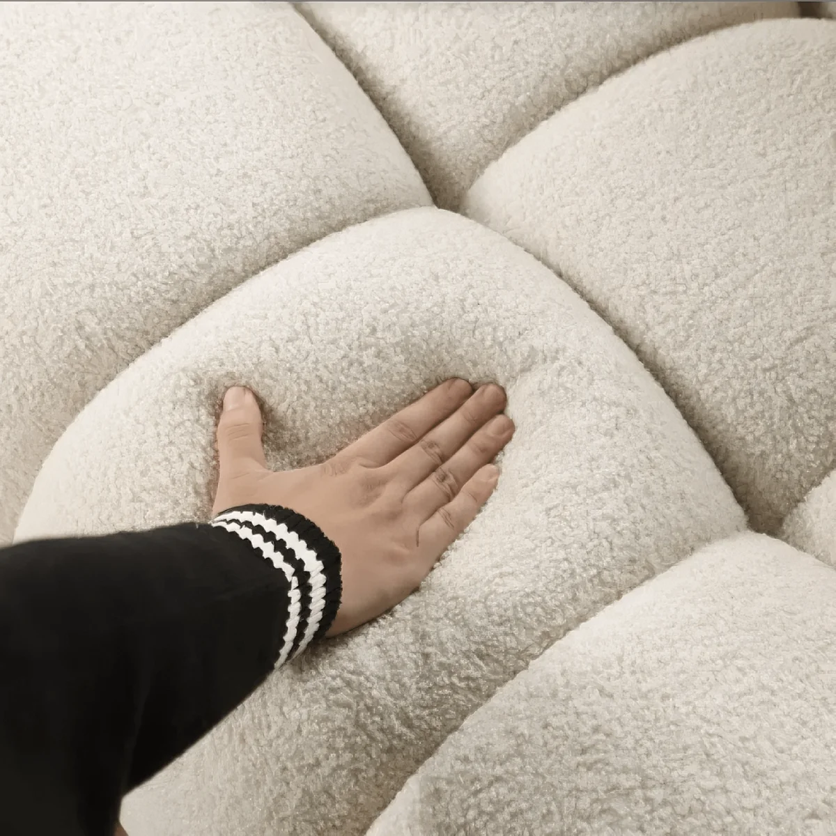 Hand touching a textured beige sofa surface