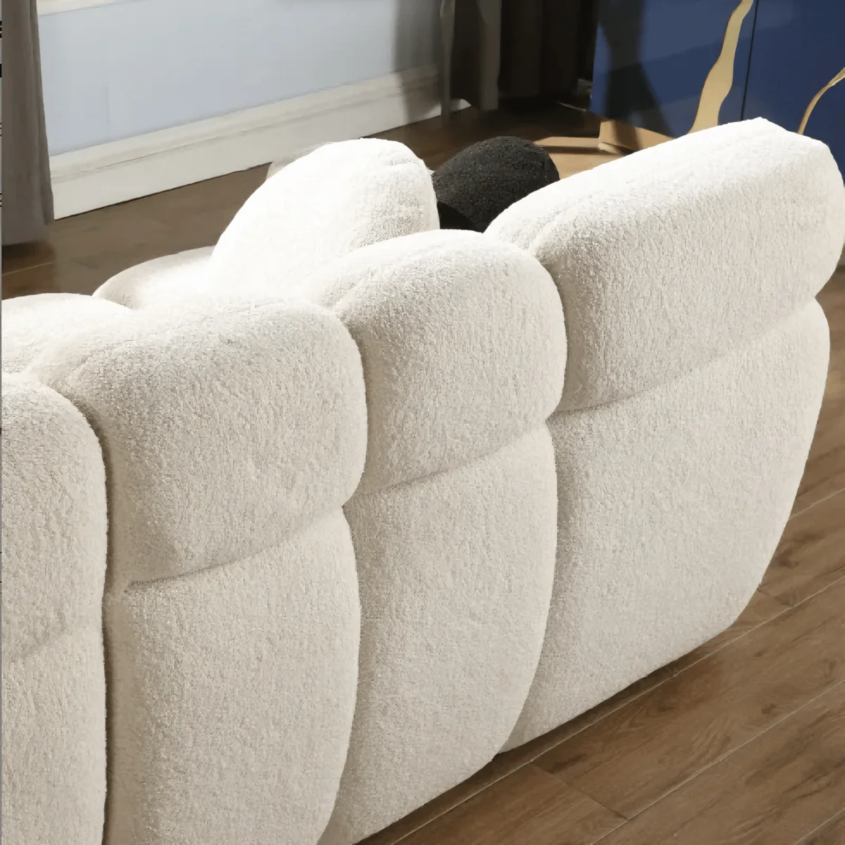 Close-up of a textured beige sofa with wooden floor and mirror in the background