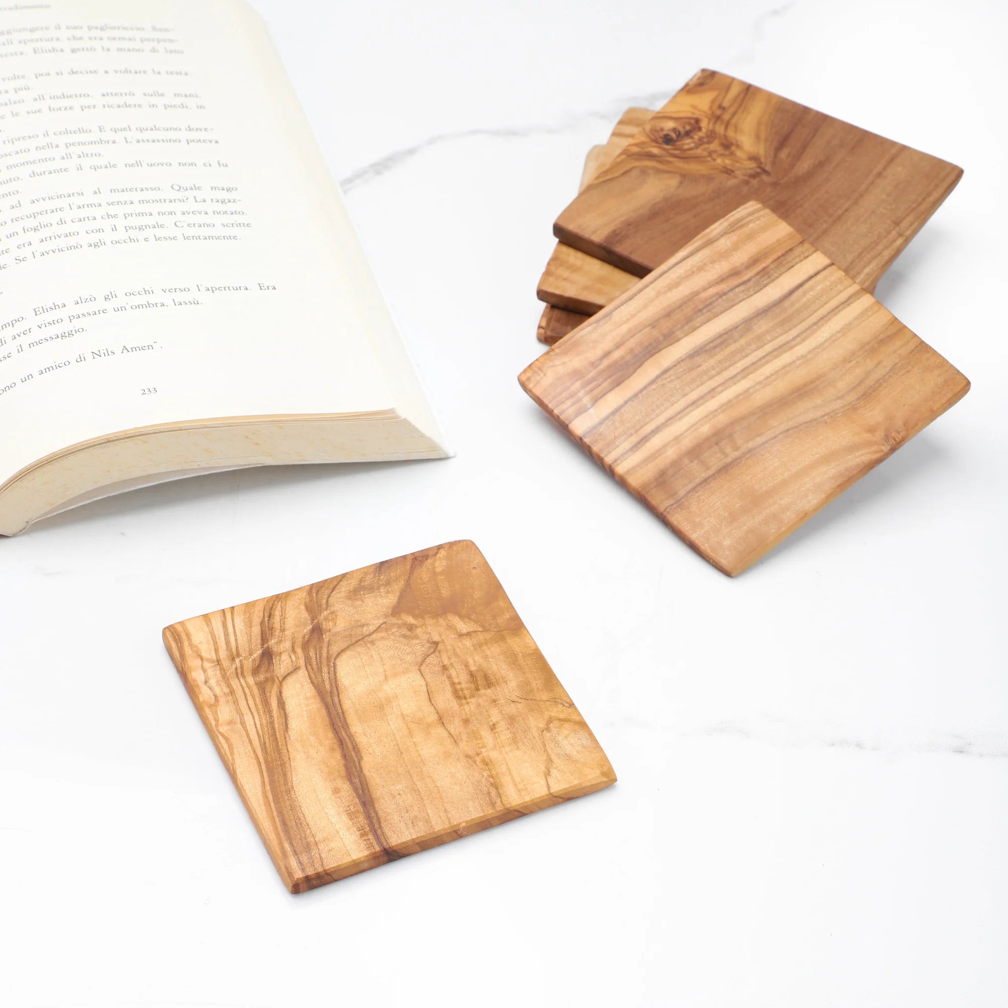 Wooden coasters on a white surface with an open book.