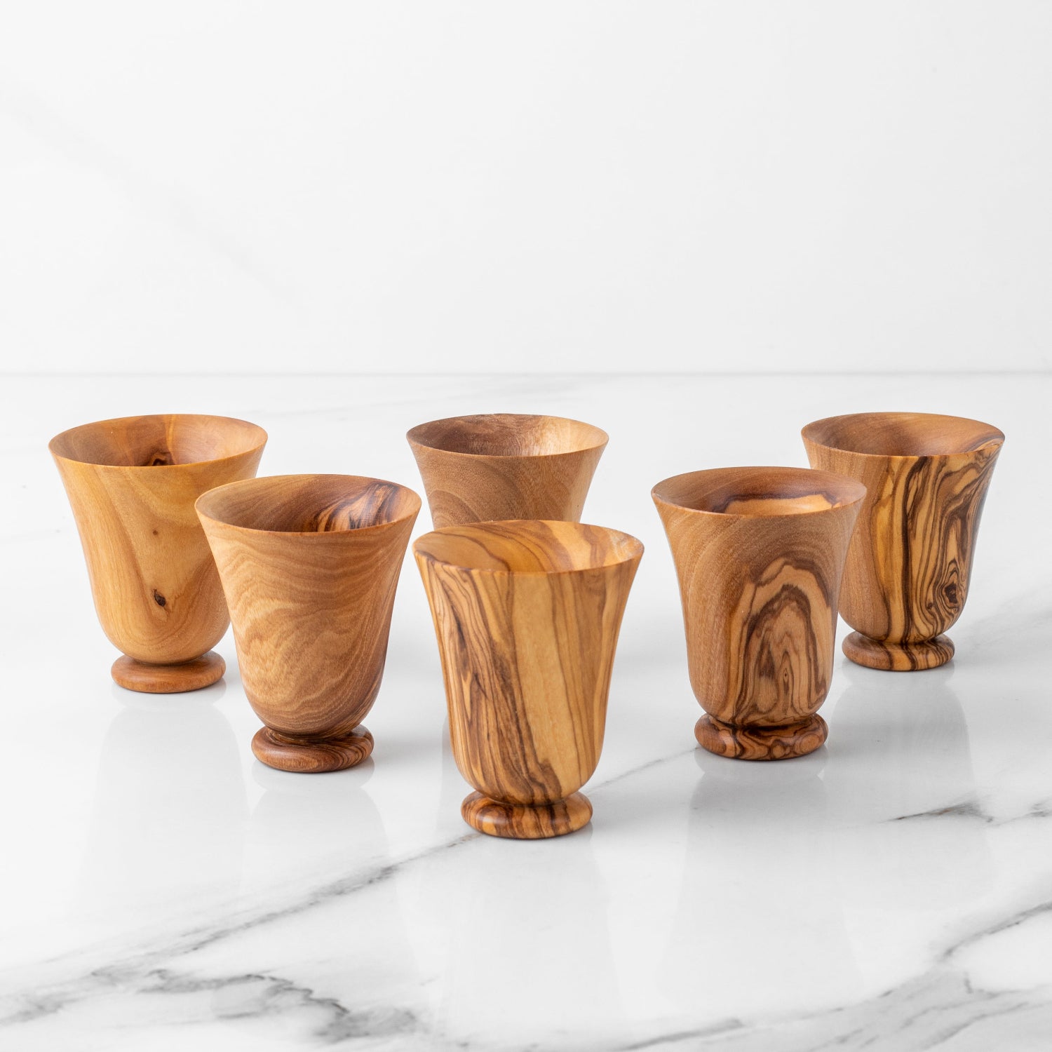 Set of six wooden tumblers on a marble surface with a white background