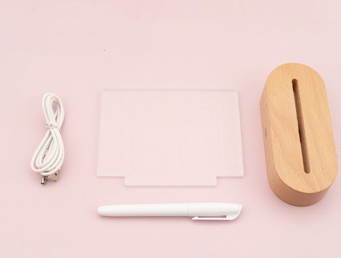 White electronic device, cable, and wooden box on a pink background