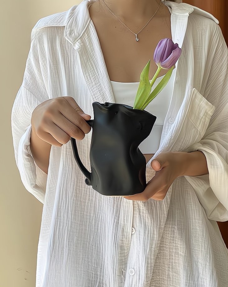 Person holding a black vase with a purple tulip against a neutral background